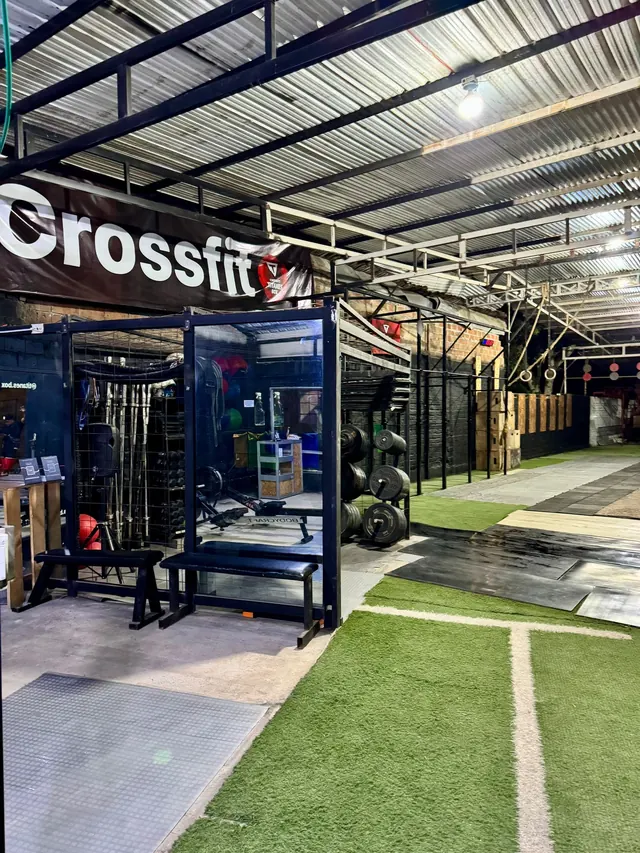 Zona de fuerza de Titanes Box con racks, barras olímpicas, discos y balones medicinales